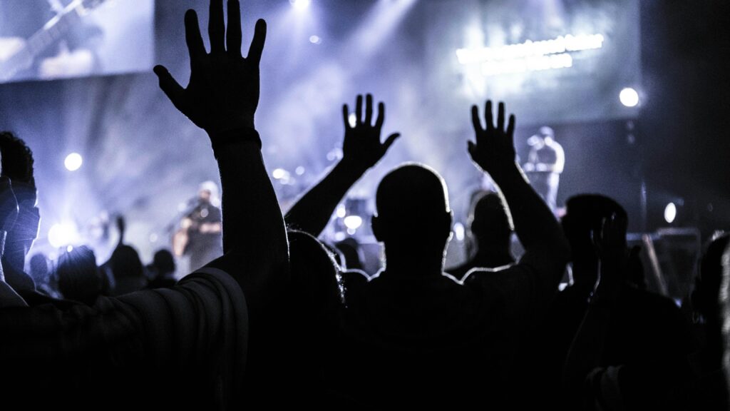 Silhouettes of an energetic audience cheering during a live concert in Houston.